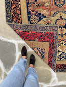 standing next to Antique Caucasian Zekhur Kuba rug